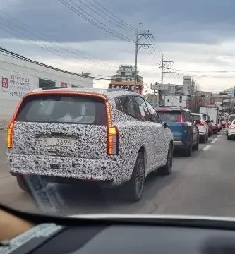 Vehículo con patrón de camuflaje circulando en una calle con tráfico.