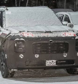 Un vehículo camuflado cubierto de nieve estacionado al aire libre.