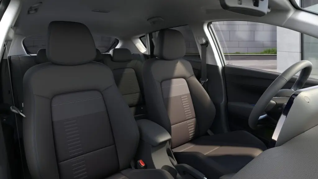Interior de un vehículo moderno con asientos de tela grises.
