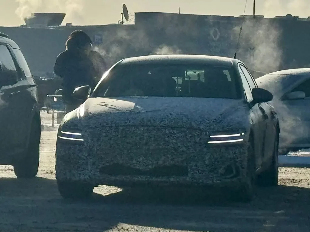 Auto cubierto de nieve con persona al lado en día soleado.