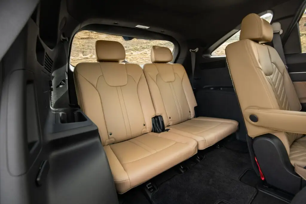 Interior trasero de un vehículo con asientos de cuero beige.