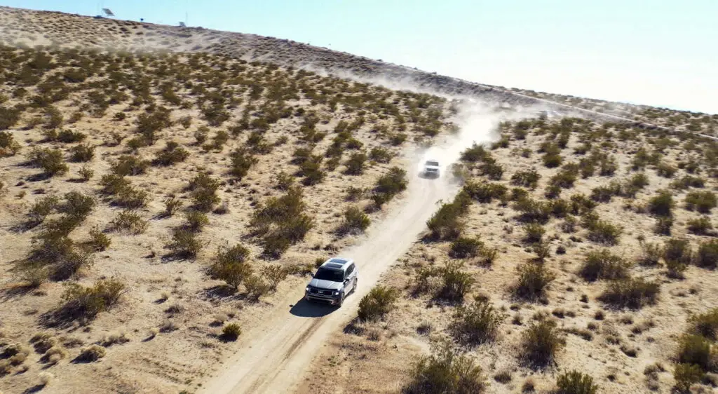 Dos vehículos transitando por un camino polvoriento en el desierto.