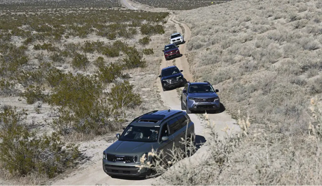 Fila de vehículos transitando por un camino rural desértico.