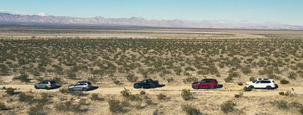 Vehículos todoterreno en fila en un desierto árido.