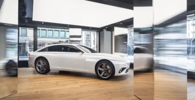 Un coche blanco expuesto en una sala con grandes ventanas.