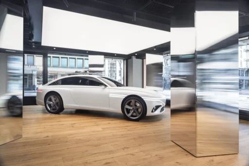 Un coche blanco expuesto en una sala con grandes ventanas.