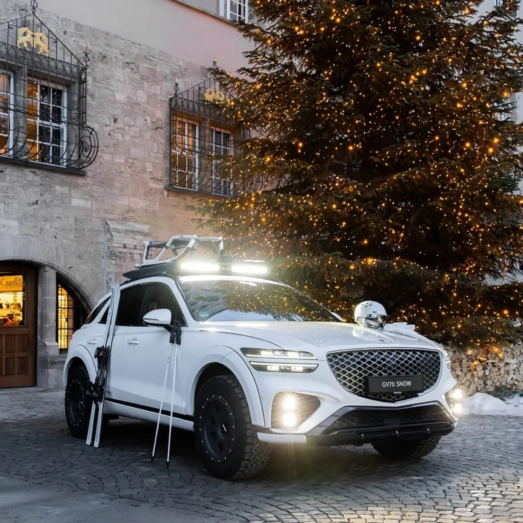 Vehículo con equipo de nieve frente a un árbol de Navidad iluminado.