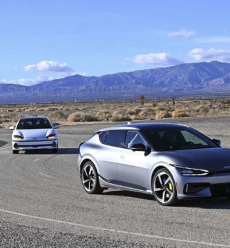 Dos coches modernos en una carretera desértica con montañas al fondo.