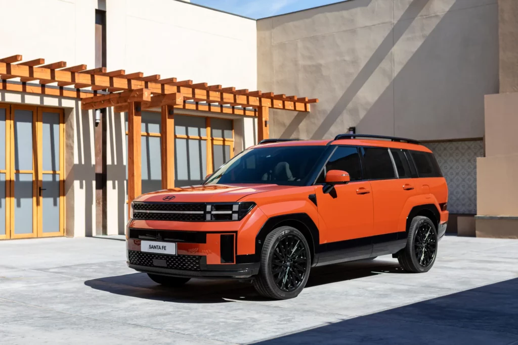 Camioneta SUV naranja estacionada en patio moderno.