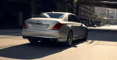 Un automóvil plateado circula por una calle soleada de la ciudad.