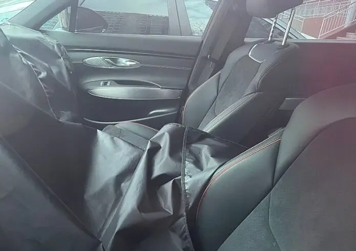 Interior de un vehículo con asientos y una chaqueta negra.