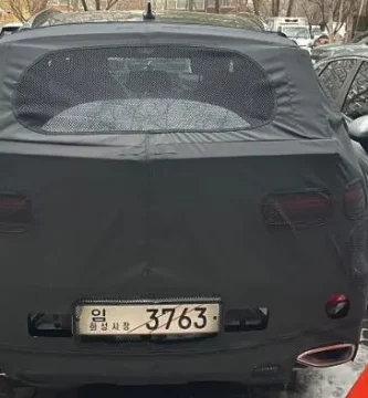 Un auto negro con una cubierta estacionado entre otros vehículos.