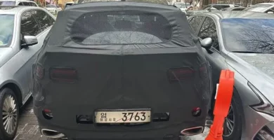 Un auto negro con una cubierta estacionado entre otros vehículos.