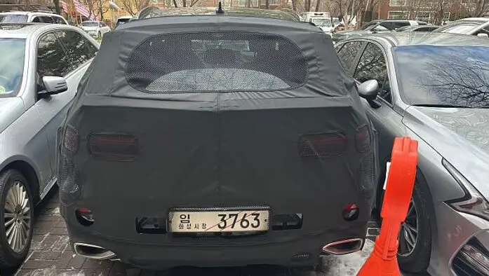 Un auto negro con una cubierta estacionado entre otros vehículos.