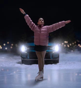 Patinadora sobre hielo frente a un auto de noche.