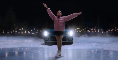 Patinadora sobre hielo frente a un auto de noche.