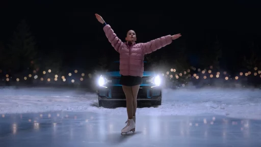 Patinadora sobre hielo frente a un auto de noche.