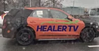 Un coche naranja con la inscripción "HEALER TV" en el costado.