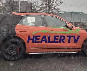 Un coche naranja con la inscripción "HEALER TV" en el costado.