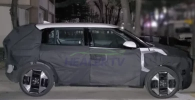 Auto parcialmente cubierto con lona en un estacionamiento nocturno.