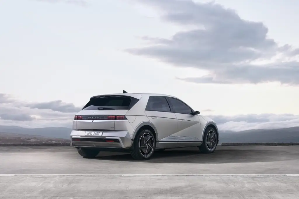 Automóvil eléctrico blanco moderno estacionado con cielo nublado de fondo.