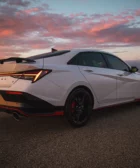 Auto deportivo blanco contra un atardecer nuboso vibrante.