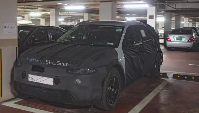 Coche con camuflaje de prueba estacionado en un garaje subterráneo.