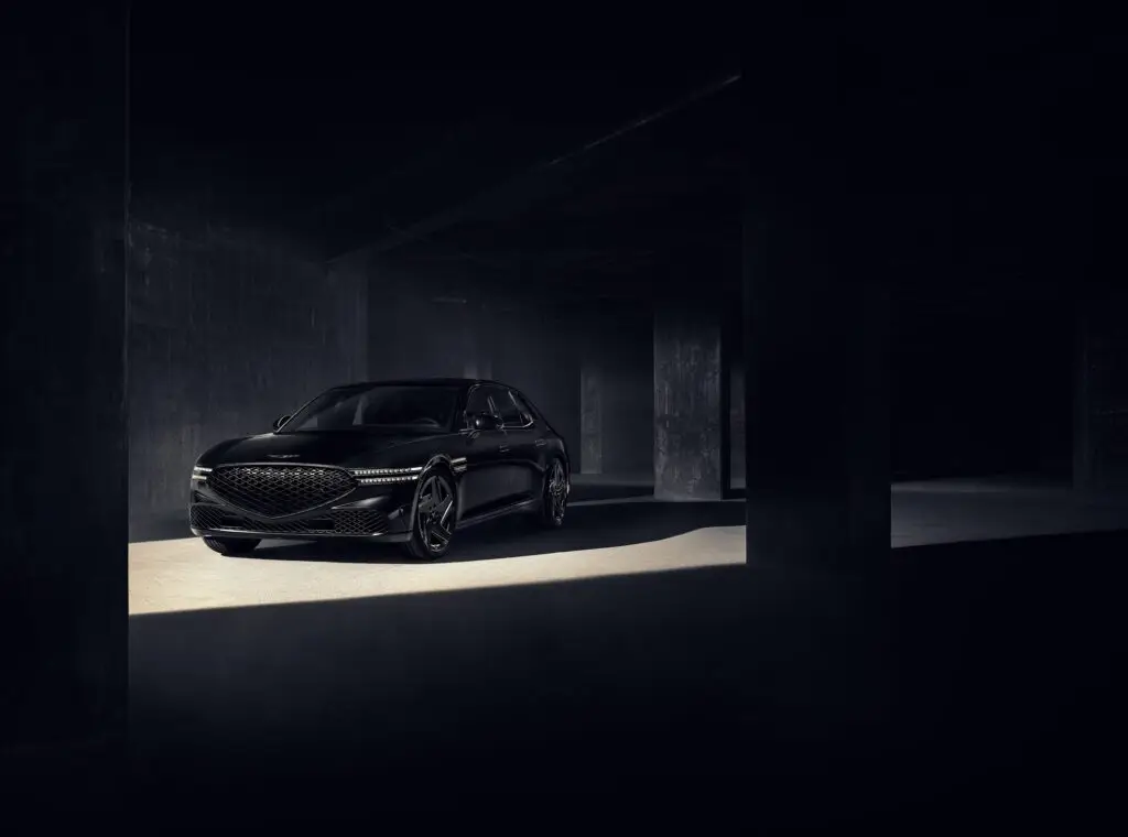Automóvil de lujo negro en un estacionamiento subterráneo oscuro.