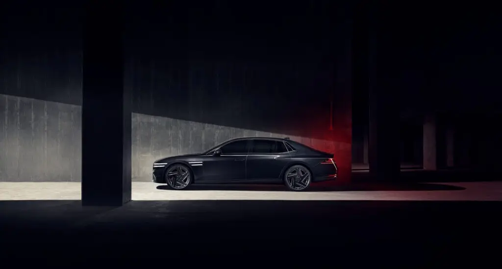 Automóvil de lujo negro estacionado en un lugar oscuro e iluminado sutilmente.