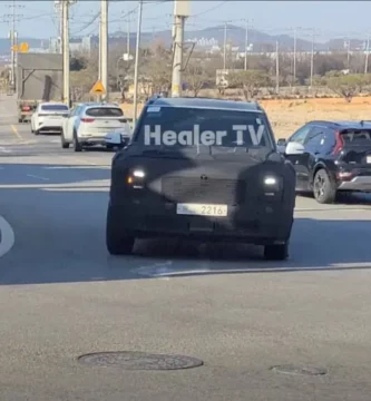 Coche con camuflaje circulando por una calle soleada.