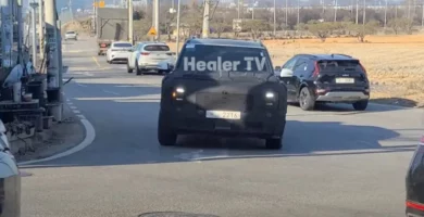 Coche con camuflaje circulando por una calle soleada.