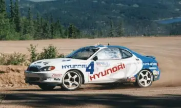 Auto de carreras Hyundai derrapando en pista de tierra.