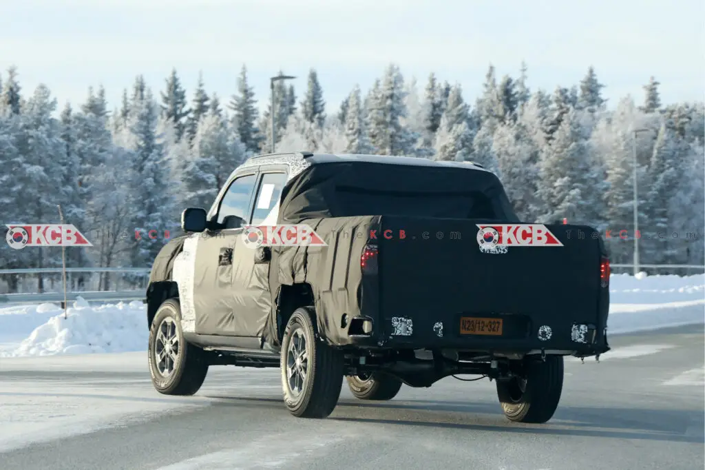 Camioneta camuflada prueba en carretera nevada y boscosa.