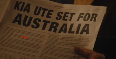 Persona sosteniendo periódico con anuncio "KIA UTE SET FOR AUSTRALIA".