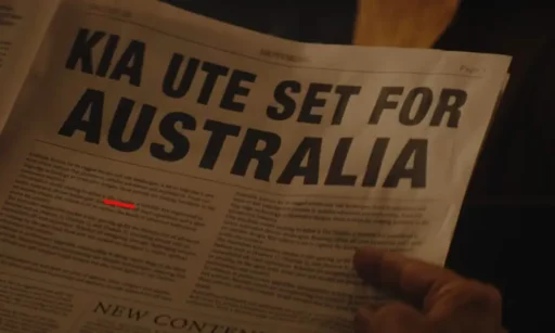 Persona sosteniendo periódico con anuncio "KIA UTE SET FOR AUSTRALIA".
