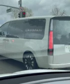 Minivan gris en la calle con semáforo en rojo.