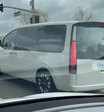 Minivan gris en la calle con semáforo en rojo.