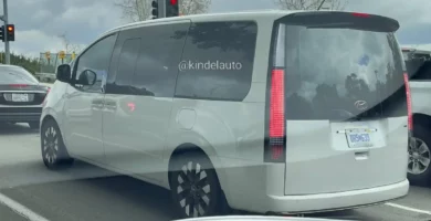 Minivan gris en la calle con semáforo en rojo.