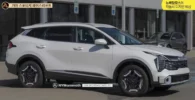 Vehículo SUV blanco Kia Sportage aparcado frente a un edificio.