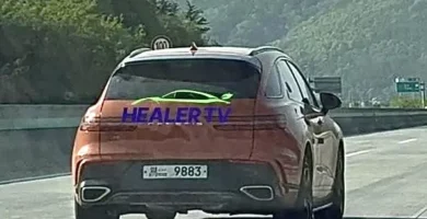 Auto naranja con texto "HEALER TV" en la autopista.