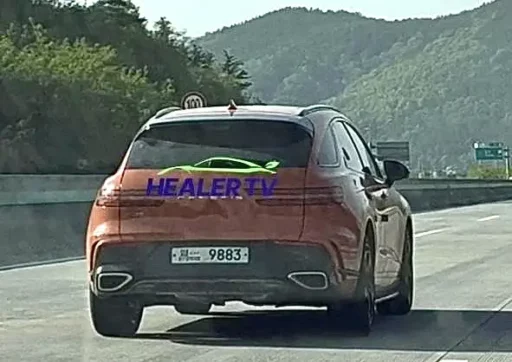 Auto naranja con texto "HEALER TV" en la autopista.