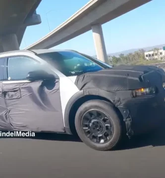 Automóvil con camuflaje de prueba en carretera y sobre puente.