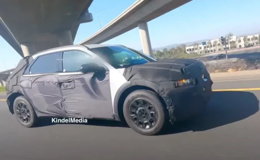 Automóvil con camuflaje de prueba en carretera y sobre puente.