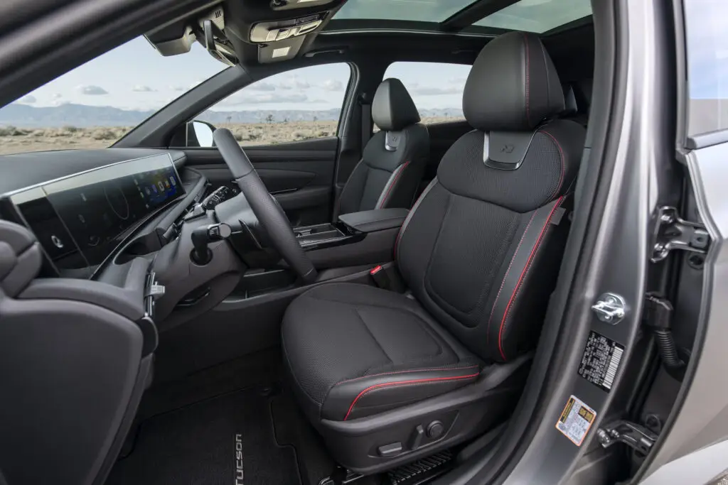 Interior de un vehículo moderno con asientos negros y pantalla digital.