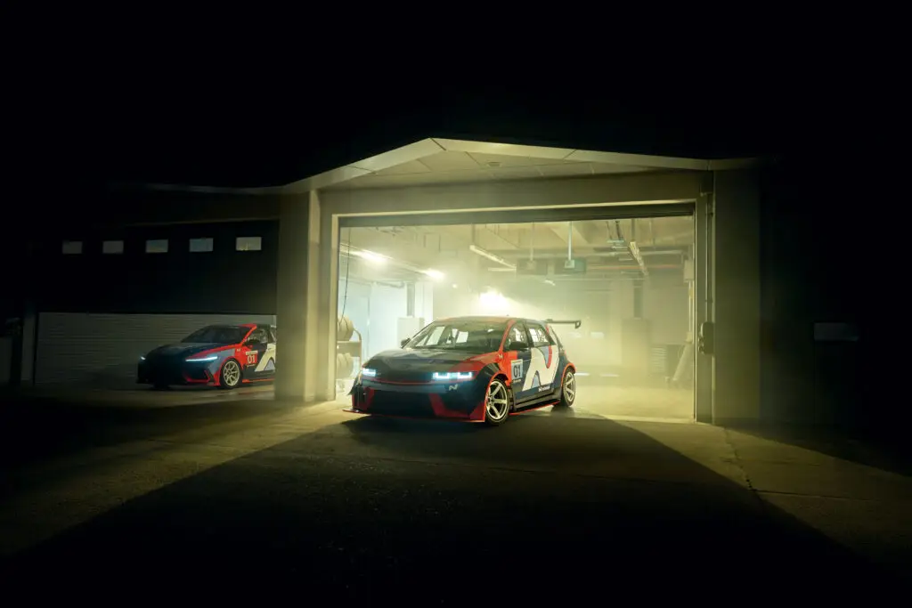 Dos coches de carreras en un garaje iluminado por la noche.