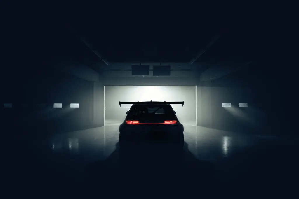 Auto deportivo en un garaje oscuro e iluminado.