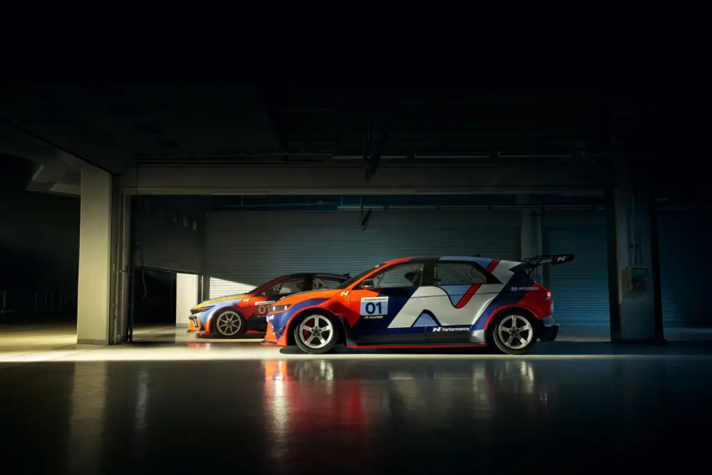 Dos coches de carreras estacionados en un garaje iluminado.