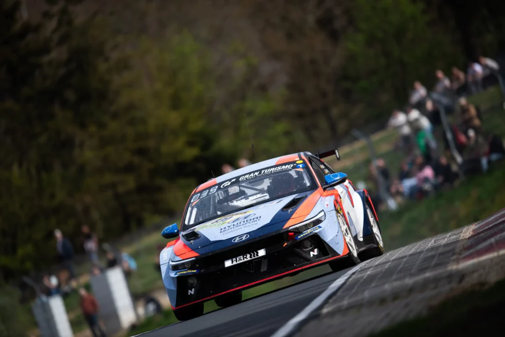 Auto de carreras Hyundai en circuito con espectadores al fondo.