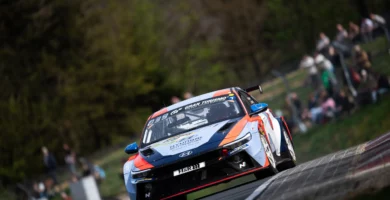 Auto de carreras Hyundai en circuito con espectadores al fondo.