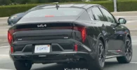 Automóvil Kia negro circulando en la carretera.